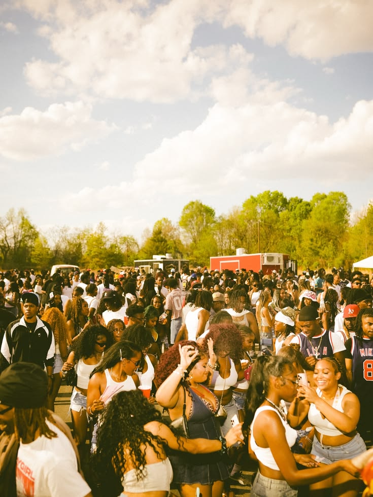 A crowd dancing in a field under a bright sky